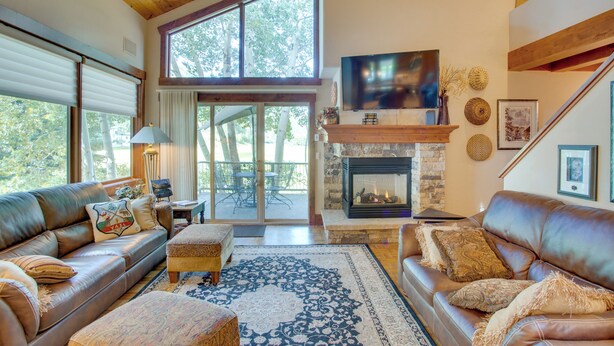 A spacious living room with leather sofas, a stone fireplace, and a large TV. - Avon Duplex Between Beaver Creek & Vail Resorts! (Avon)