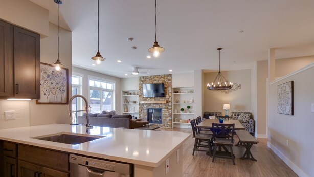 A spacious kitchen with a central island, a dining area with a chandelier, and a living room with a fireplace. - Stunning Winter Park Condo Near Slopes! (Winter Park)