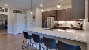 A modern kitchen with a large island, stainless steel appliances, and pendant lighting. - Stunning Winter Park Condo Near Slopes! (Winter Park)