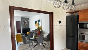 Una cucina moderna con un frigorifero nero LG, mobili in legno e un'area pranzo con tavolo e sedie in vetro.