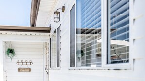 A white building with a porch, a hanging plant, and a sign that reads "Life is good at the beach."
