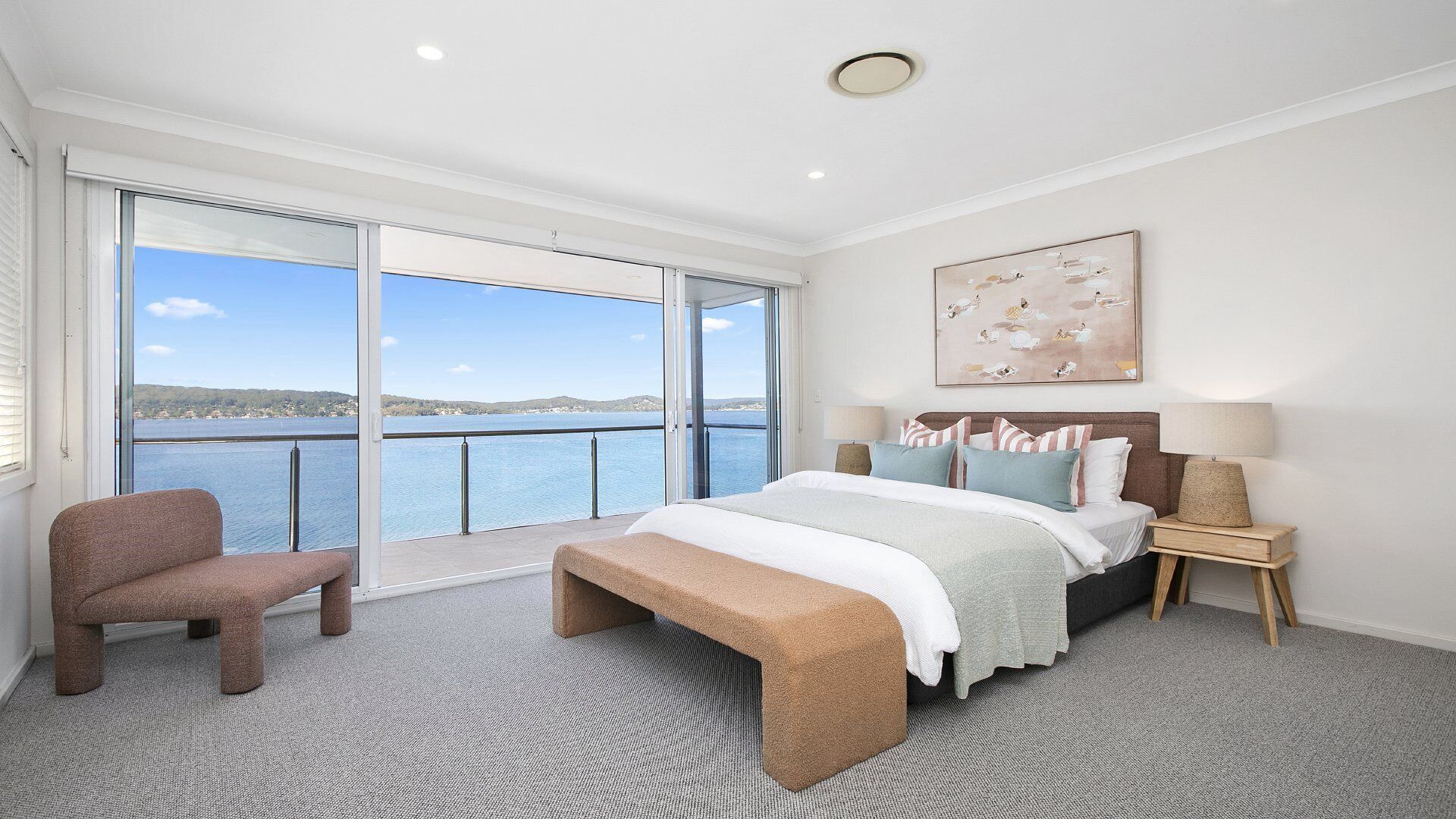 A bedroom with a large bed, a chair, a bench, a nightstand, and a painting.