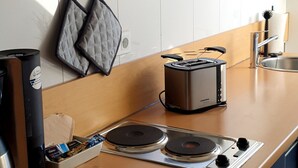 A kitchen with a microwave, toaster, kettle, and a coffee maker.