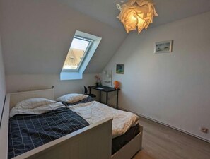 Ein Schlafzimmer mit Oberlicht, einem Bett mit Kopfteil, einem Schreibtisch und einem Stuhl.