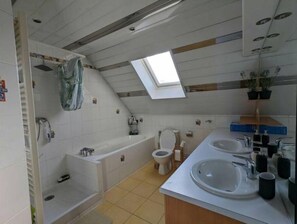Bathroom features a bathtub, toilet, and double sink with a mirror.