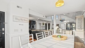 Een moderne keuken met witte kasten, een eethoek met een witte tafel en stoelen, en een trap naar een verdieping.