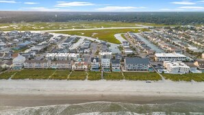 Luchtbeeld van een kustgebied met woningen, een strand en een rivier.