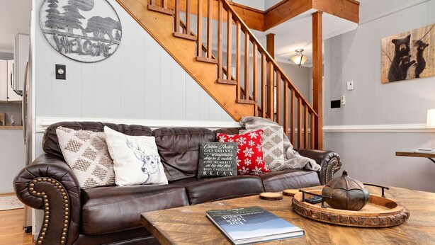 A living room with a brown leather sofa, wooden coffee table, and a staircase.