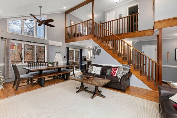 A spacious living area with a wooden staircase, a dining table, and a sofa.