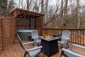 Una terrazza esterna con vasca idromassaggio, due poltrone Adirondack e un braciere.