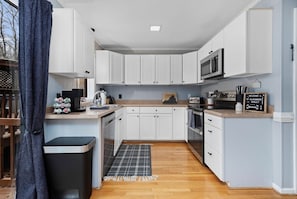 Una cocina compacta con armarios blancos, un microondas y un letrero en una pizarra.