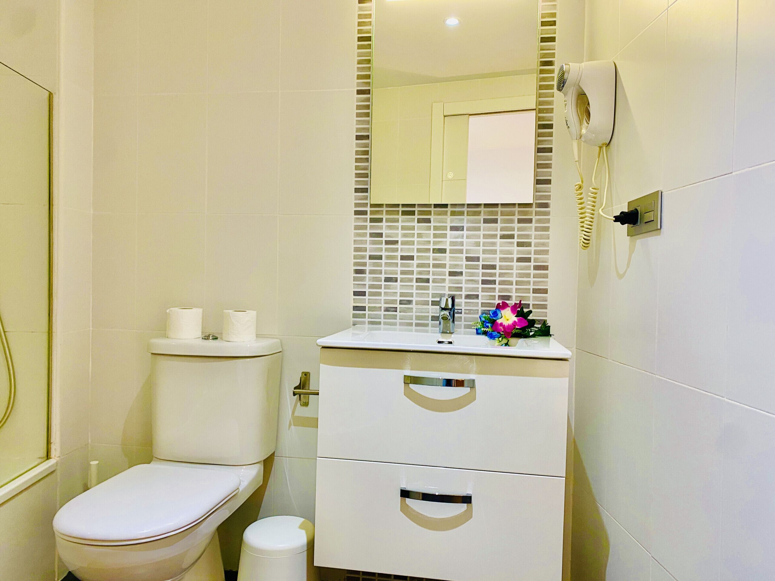 Un bagno piccolo e pulito, con il water, un lavandino e uno specchio.