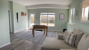 Un salon spacieux avec un canapé beige, une table basse en bois et un tapis à motifs.