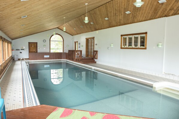 An indoor swimming pool with wooden beams on the ceiling, a tiled floor, and a wooden deck area. - Rita's Retreat: The Bachelor ~ Indoor Saltwater Pool ~ with Lake View! (Sydney)