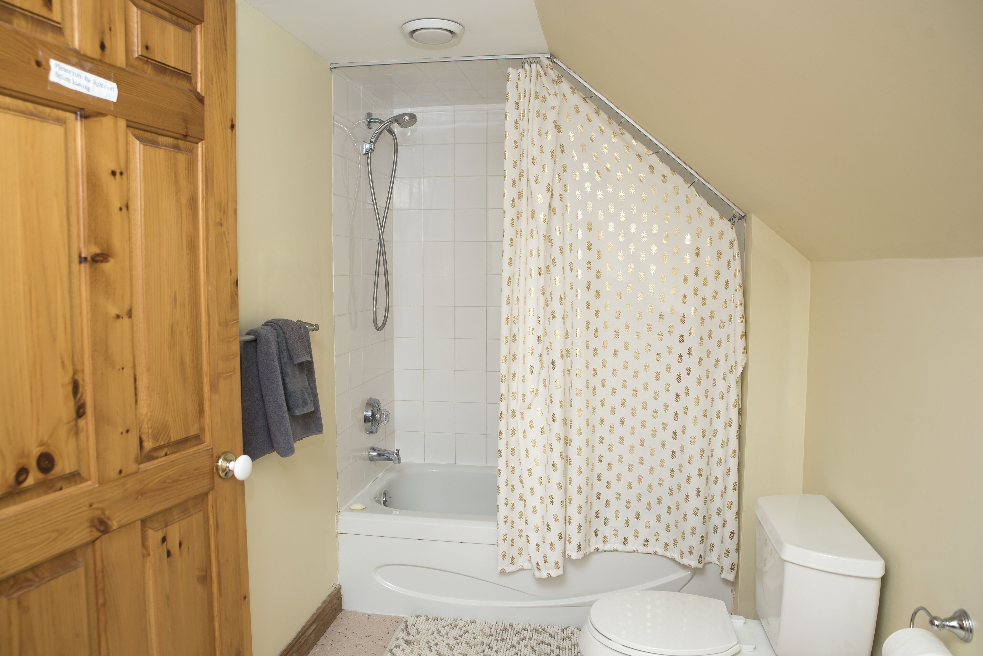A bathroom with a bathtub, toilet, and wooden cabinets.