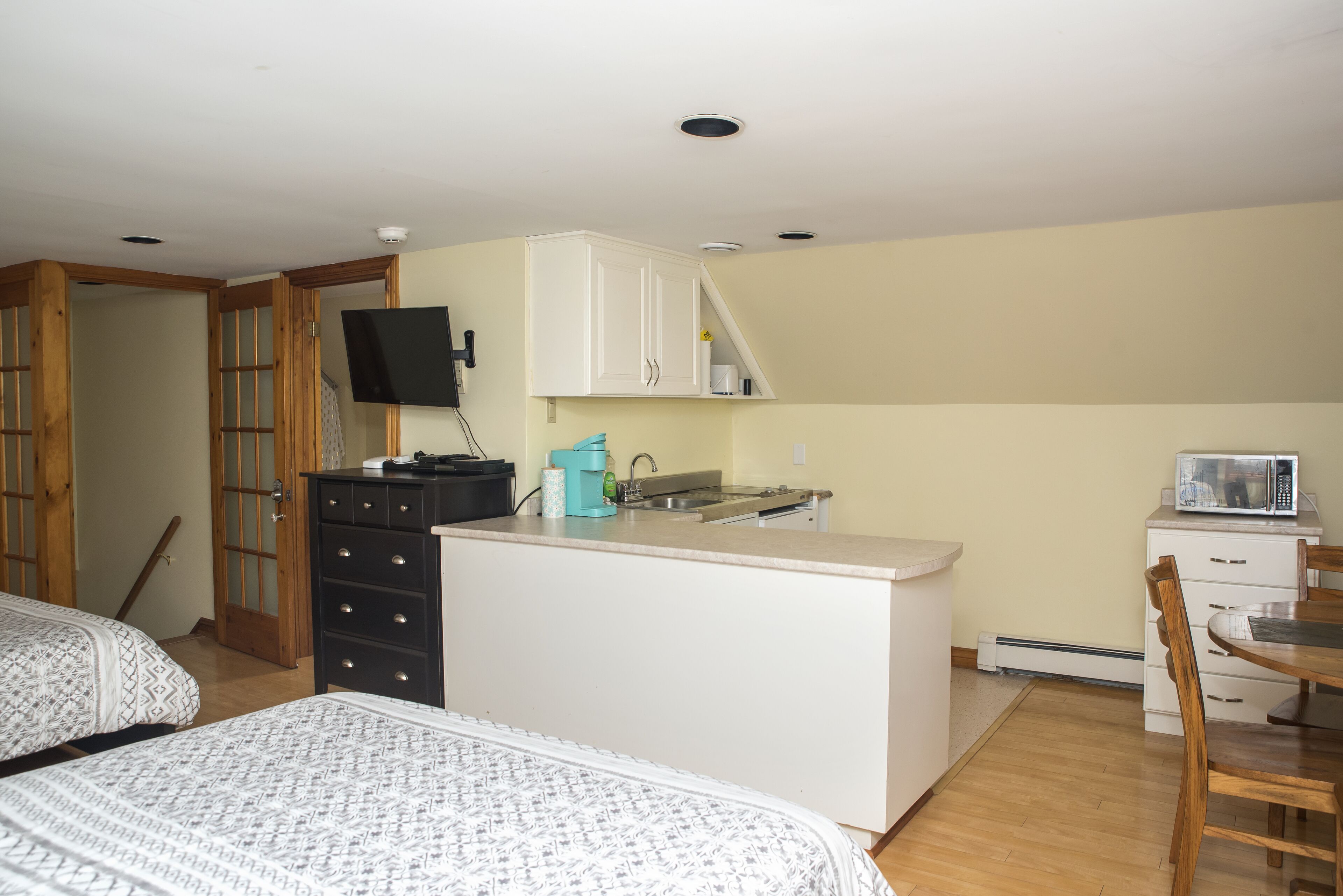 Een compacte kamer met kitchenette, een bed en een kleine eethoek.