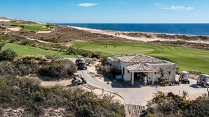 Ein Golfplatz mit Blick auf den Ozean, ein Clubhaus und eine Wüstenlandschaft.
