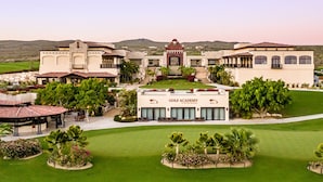 Eine Golfakademie mit einem großen Gebäude, angelegten Gärten und Blick auf die umliegenden Hügel.