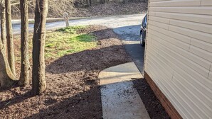 Eine hölzerne Bank in einem Garten mit Mulch und Bäumen.