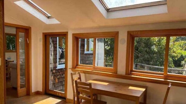 Una habitación con tragaluces, ventanas amplias, una mesa de madera y sillas.