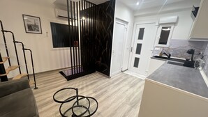 A modern kitchen with a grey countertop, a black metal rack, and a white door with glass panels.