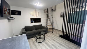 A modern living room with a grey sofa, a coffee table, and a unique light fixture.
