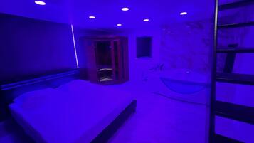 Une chambre à coucher comprenant un lit, une banquette intégrée, une baignoire et un petit espace clos avec une porte.