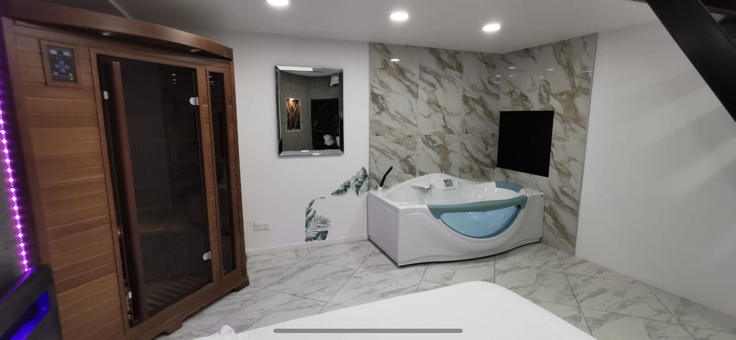 A modern bathroom with a glass-enclosed shower, a freestanding bathtub, and a marble-patterned wall.