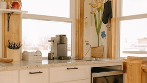 Una cucina con mobili bianchi, una macchina da caffè e un forno a microonde.