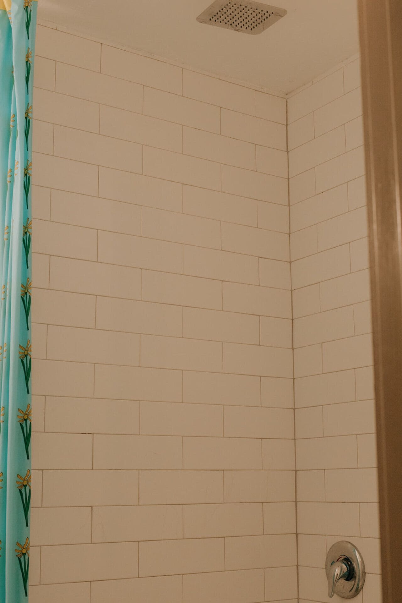 Esquina de un baño con paredes de azulejos blancos y desagüe de ducha.