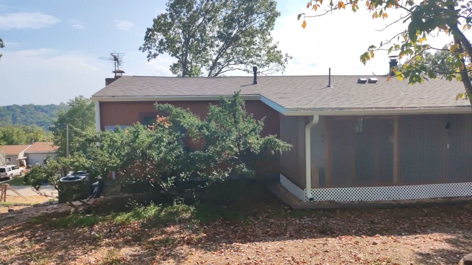 A two-story house with a visible chimney, a covered porch, and a tree in front.