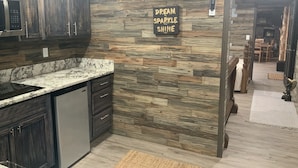 A modern kitchen with dark wooden cabinets, a granite countertop, and a motivational wall sign. - Cedar house (Rockaway Beach)