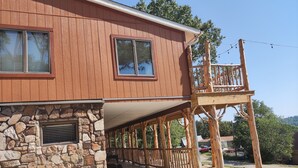 A two-story building with a stone foundation, wooden exterior, and a balcony with a wooden railing. - Cedar house (Rockaway Beach)