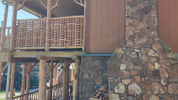 A rustic cabin with a stone chimney, wooden deck, and a stone wall. - Cedar house (Rockaway Beach)