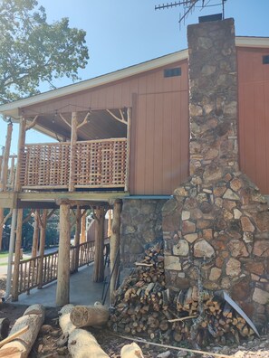 A rustic cabin with a stone chimney, wooden deck, and a stone wall. - Cedar house (Rockaway Beach)