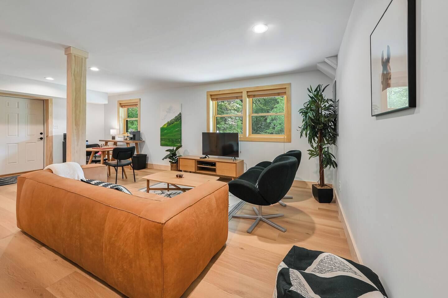 A modern living room with a sofa, a TV, a desk, and a plant.