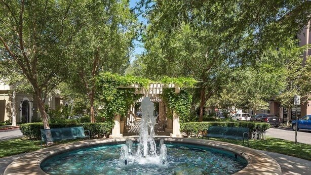 Ein runder Brunnen mit Fontänen in der Mitte, umgeben von einem steinernen Rand.