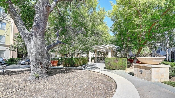 A landscaped outdoor area with a curved pathway, a pergola, and a large planter. - Sky Luxury 2BDRM Suite | Deluxe Living Cali (Valencia)