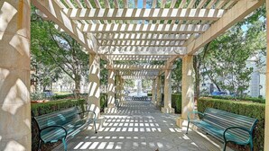 A covered walkway with benches, stone columns, and a patterned floor. - Sky Luxury 2BDRM Suite | Deluxe Living Cali (Valencia)