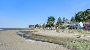 En fastighet vid stranden med flera hus, en sandstrand och en klarblå himmel.