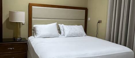 A neatly made bed with white linens in a hotel room.