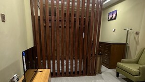A room with a wooden partition, a desk with a computer, a chair, and a lamp. - ACHIE SUITES (Accra)