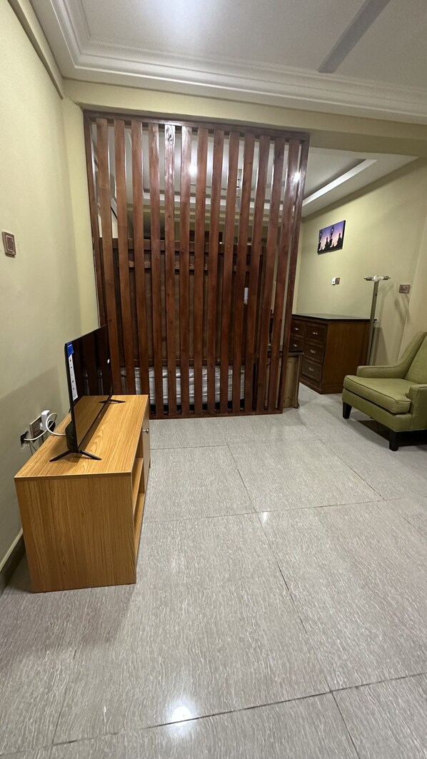 A room with a wooden partition, a desk with a computer, a chair, and a lamp.