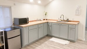 A compact kitchen with grey cabinets, a microwave, a refrigerator, and a sink. - The Modern Cottage in Rural Lake Stevens (Lake Stevens)