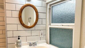 A bathroom with a white sink, a wooden-framed mirror, and a window with frosted glass. - The Modern Cottage in Rural Lake Stevens (Lake Stevens)