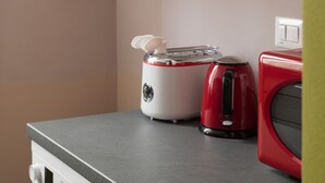 Et køkken med en hvid og rød toaster, en rød elkedel og en grå bordplade.