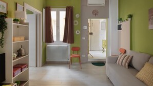 En stue med sofa, fjernsyn, reol og radiator.