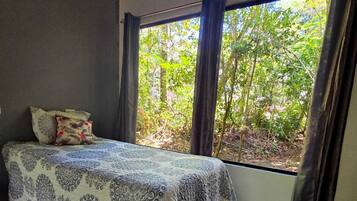 A bedroom with a bed, curtains, and a view of trees.