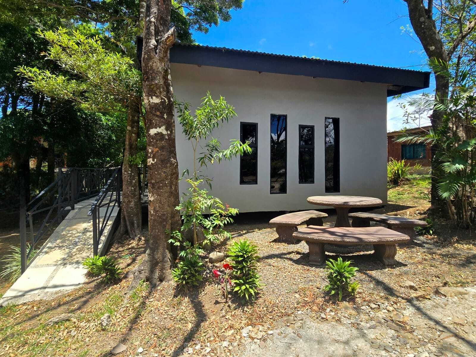 A small building with a flat roof, a paved pathway, and a seating area with benches.