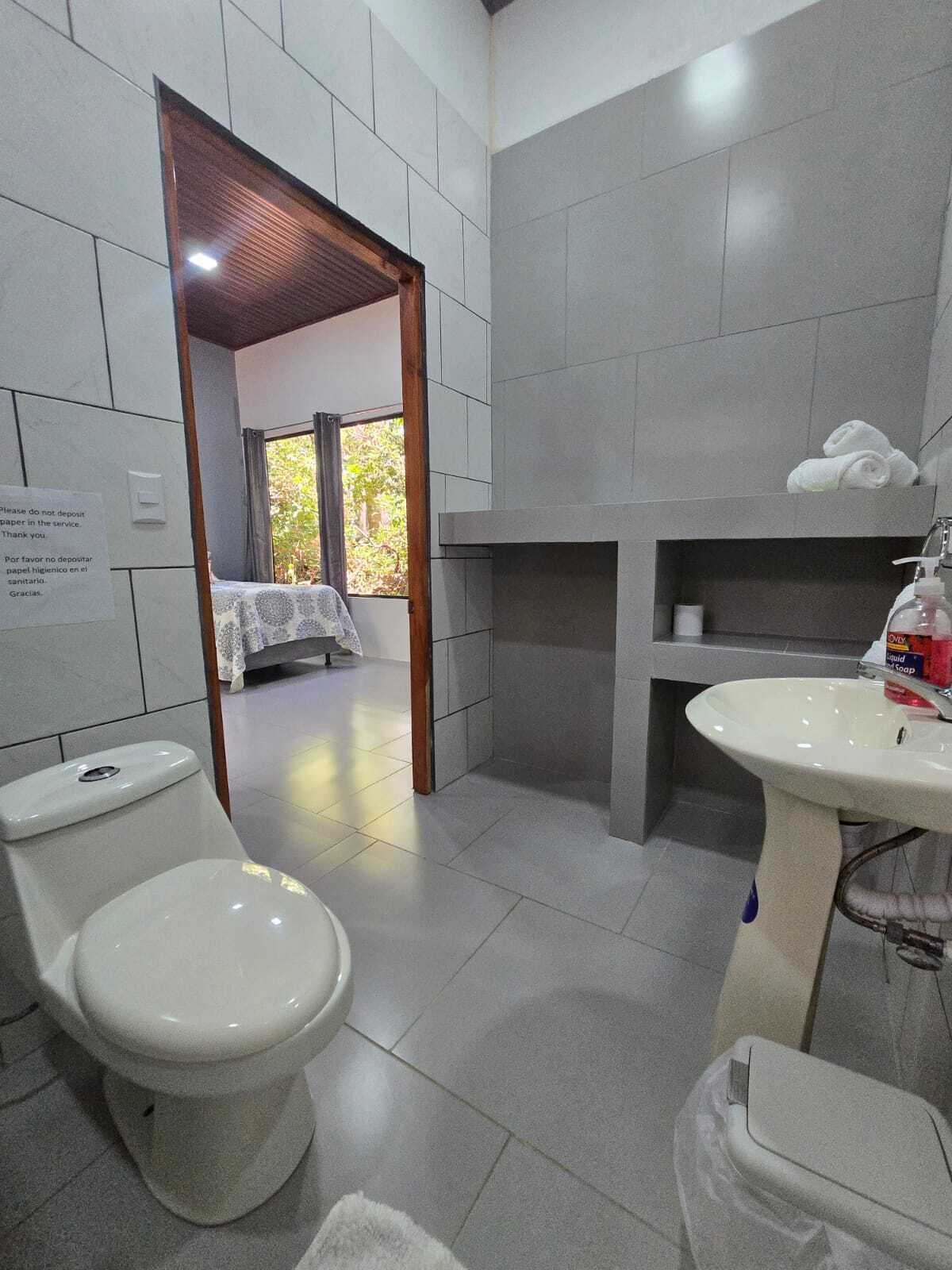 Um banheiro moderno com vaso sanitário, pia e área de chuveiro.